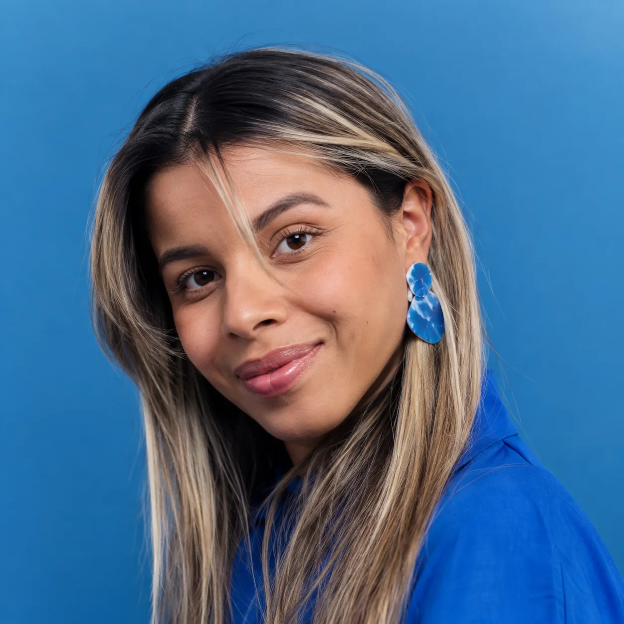 Retrato de Stella Borges usando blusa azul, diante de um fundo azul