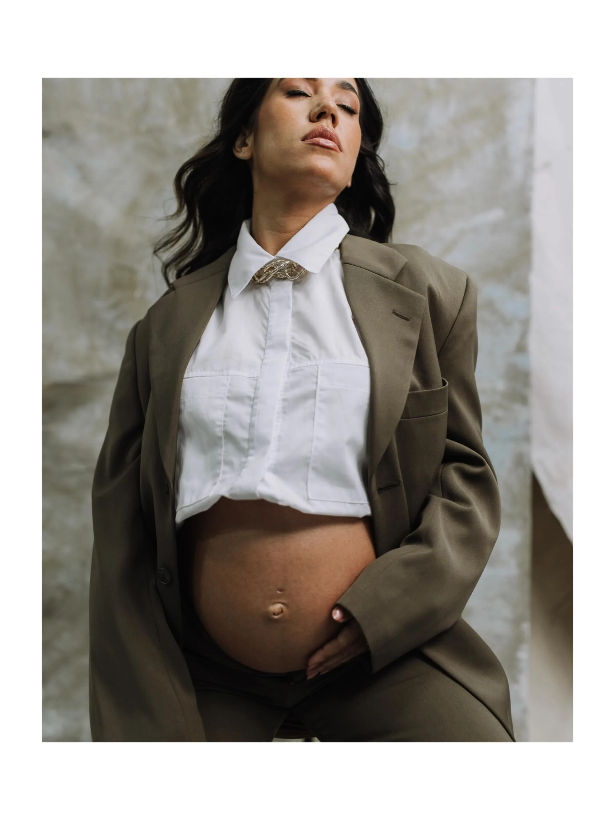 Mulher de camisa branca e blazer verde posa com o rosto voltado para a luz em fotografia com borda branca